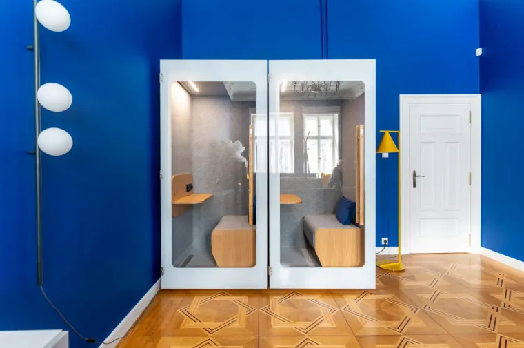 Two HIDE H1 acoustic booths with a bench seat in a law firm with deep blue walls
