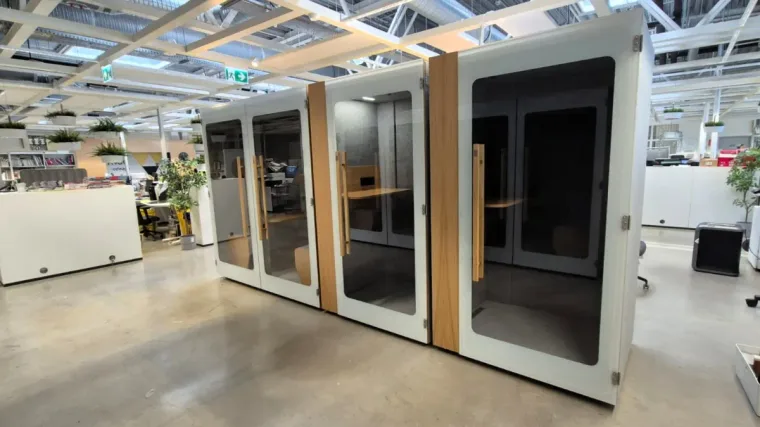 A row of HIDE H1+ acoustic booths in an open industrial-style office hall