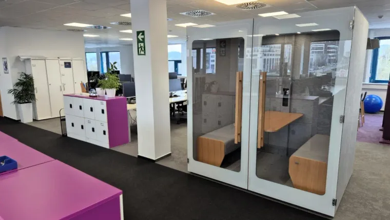 HIDE H4 acoustic booth in an open-plan office with pink furniture and a city view through the window