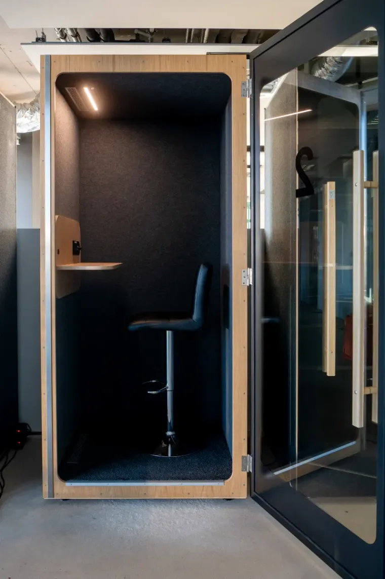 Open HIDE H1 acoustic booth with a dark interior and a tall black bar stool