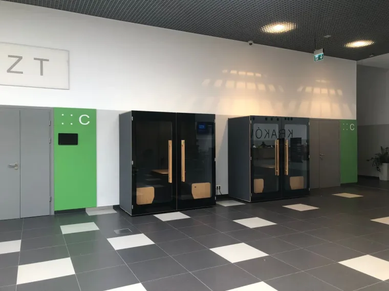 Vier dunkle HIDE H2 Akustikkabinen in einer Kongresshalle mit Schachbrettboden