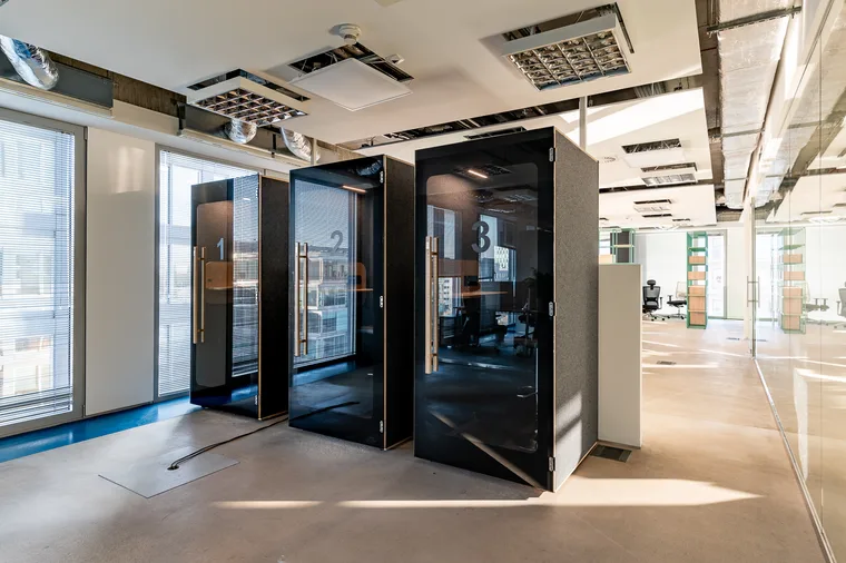 A row of three black HIDE H1 acoustic booths marked 1-3 next to a glazed wall