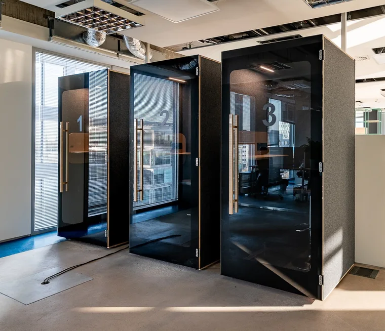 Three black HIDE H1 acoustic booths numbered 1-3, side view by the windows