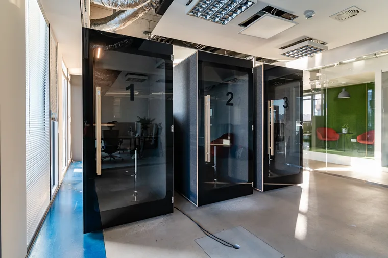 Three black HIDE H1 acoustic booths numbered 1-3, with a green moss-wall meeting room visible behind