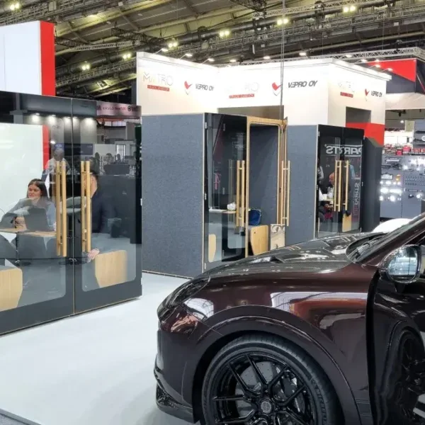 Kwadratowa miniatura kabiny akustycznej HIDE H4 na stoisku FroGum Automechanika, obok samochód