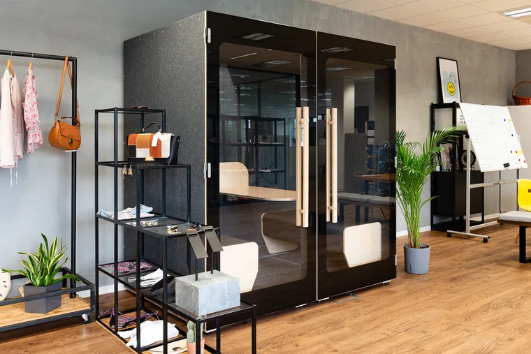 Large HIDE H4 acoustic booth in a fashion store, surrounded by clothing racks