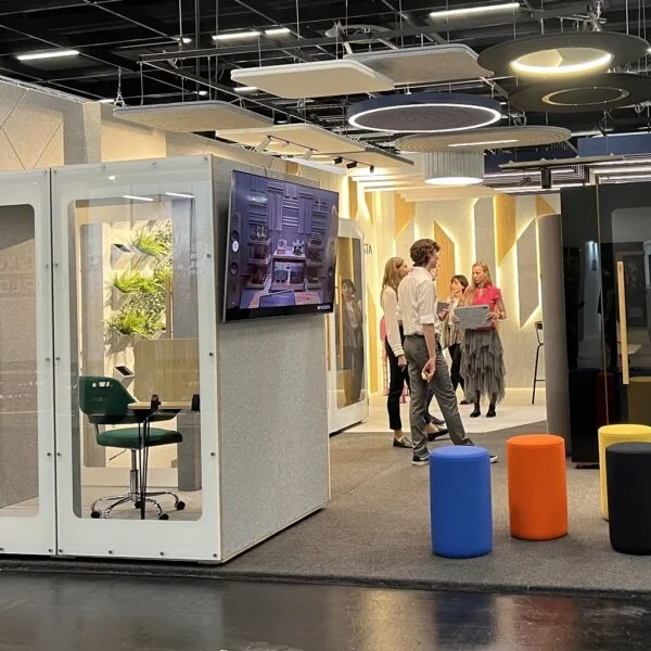 Square thumbnail of a HIDE Mini Office booth at a trade fair stand with a TV screen and colourful stools